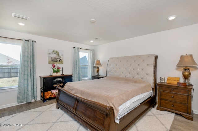 bedroom with light hardwood / wood-style floors and a textured ceiling