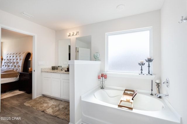 bathroom featuring vanity, wood-type flooring, and a tub