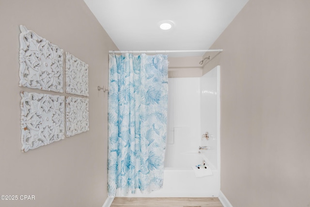 full bath featuring shower / tub combo, wood finished floors, and baseboards