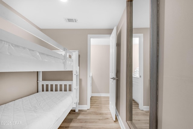 bedroom with visible vents, baseboards, and wood finished floors