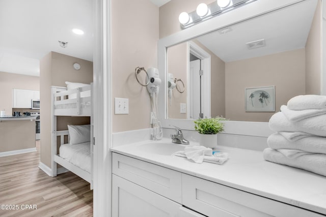 bathroom with visible vents, vanity, and wood finished floors