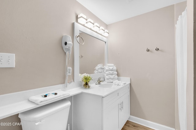 full bathroom with toilet, baseboards, wood finished floors, and vanity