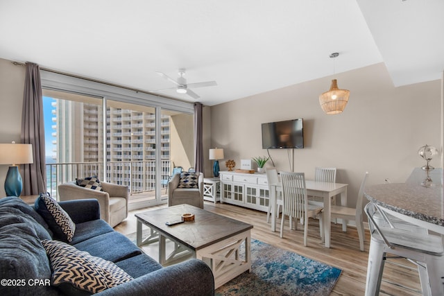 living room featuring wood finished floors, a ceiling fan, and baseboards