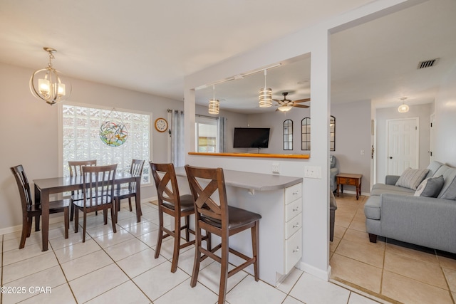 kitchen with light tile patterned flooring, decorative light fixtures, a breakfast bar, and ceiling fan with notable chandelier