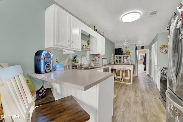 kitchen featuring a breakfast bar, sink, kitchen peninsula, stainless steel appliances, and white cabinets