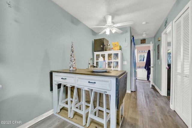 kitchen featuring white cabinetry, wooden counters, ceiling fan, and light hardwood / wood-style flooring