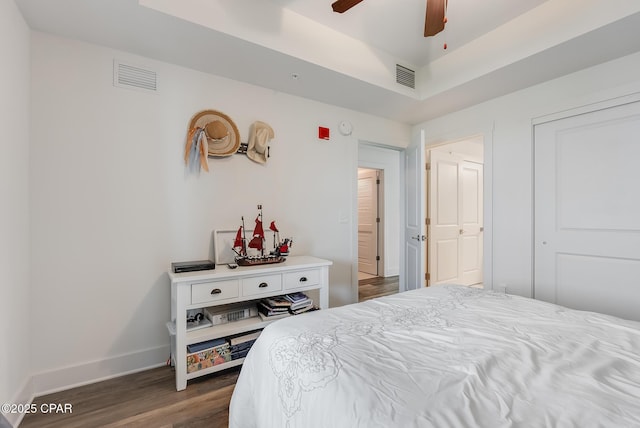 bedroom with ceiling fan, a tray ceiling, and dark hardwood / wood-style flooring