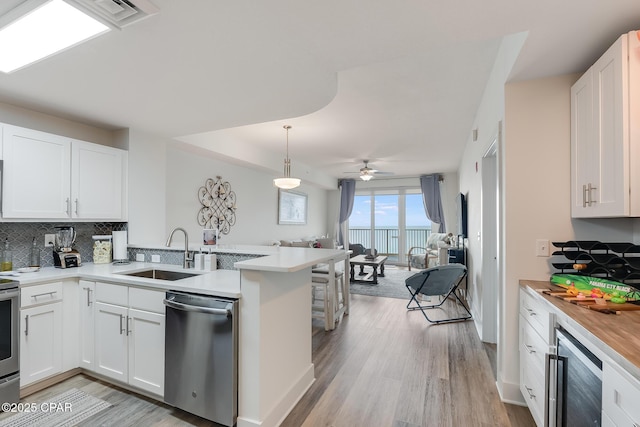 kitchen featuring sink, white cabinetry, beverage cooler, stainless steel dishwasher, and kitchen peninsula