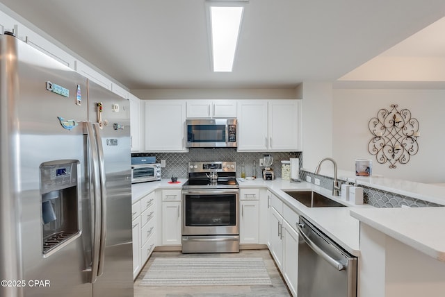 kitchen featuring white cabinetry, sink, backsplash, kitchen peninsula, and stainless steel appliances