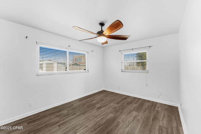 spare room featuring dark wood-type flooring, a wealth of natural light, and ceiling fan