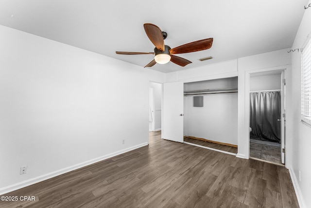 unfurnished bedroom with ceiling fan, a wall mounted AC, and dark hardwood / wood-style flooring