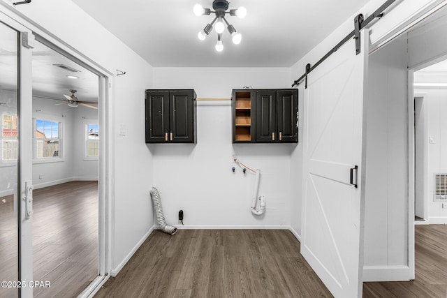 laundry area featuring dark hardwood / wood-style floors, cabinets, a barn door, and ceiling fan