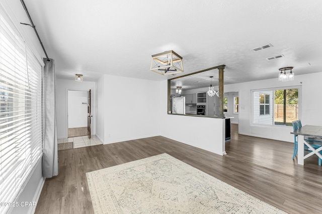 hall featuring hardwood / wood-style flooring, a textured ceiling, and a chandelier