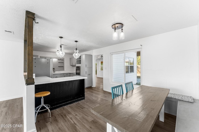 kitchen with gray cabinetry, dark hardwood / wood-style floors, a kitchen breakfast bar, and kitchen peninsula