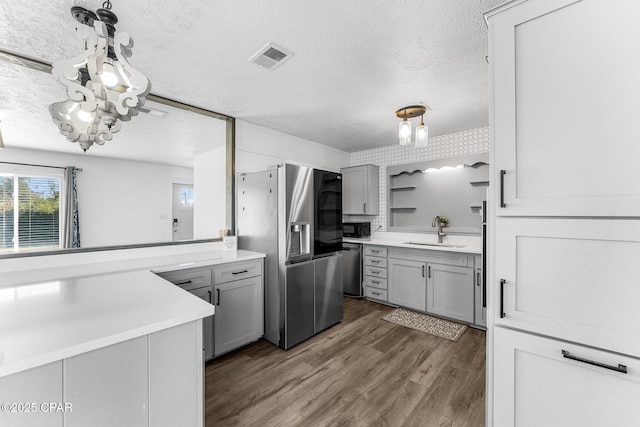 kitchen with sink, gray cabinetry, stainless steel appliances, dark wood-type flooring, and a textured ceiling