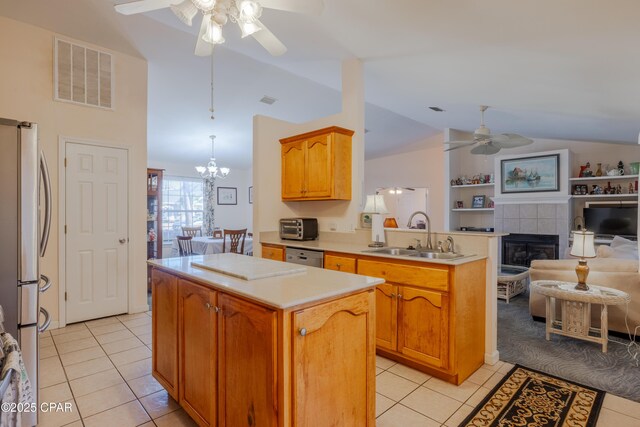 kitchen with sink, appliances with stainless steel finishes, a center island, vaulted ceiling, and kitchen peninsula