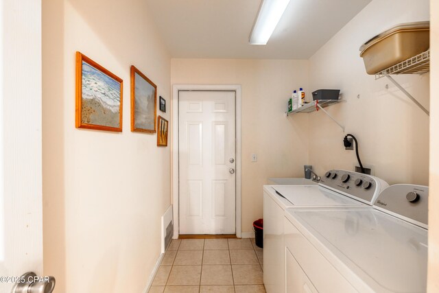 clothes washing area with washer and dryer and light tile patterned floors