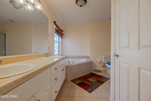 bathroom with toilet, vanity, tiled bath, and tile patterned flooring