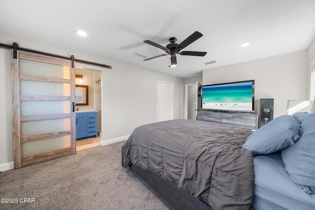 carpeted bedroom with a barn door, connected bathroom, ceiling fan, and a closet