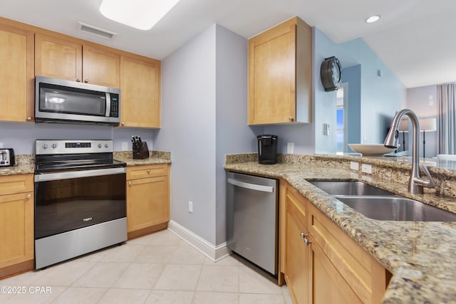 kitchen with sink, light tile patterned floors, stainless steel appliances, light stone countertops, and light brown cabinets