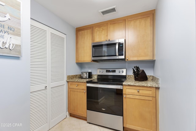 kitchen featuring light stone counters, stainless steel appliances, and light brown cabinets