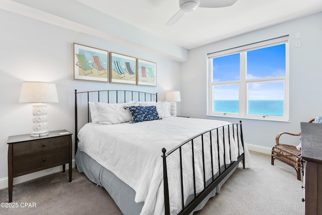 carpeted bedroom featuring a water view and ceiling fan