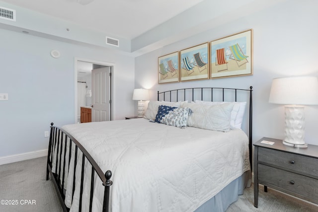 bedroom featuring ensuite bathroom and light carpet