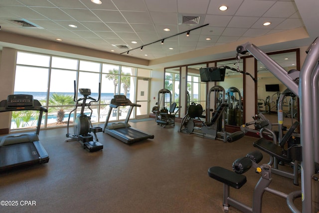 workout area with rail lighting and a drop ceiling