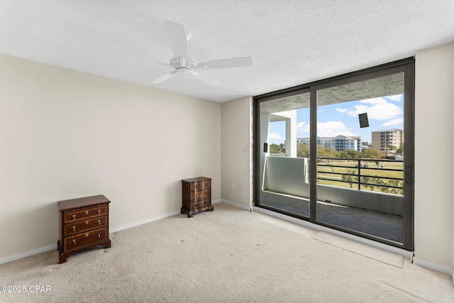 carpeted spare room featuring ceiling fan, a textured ceiling, and baseboards