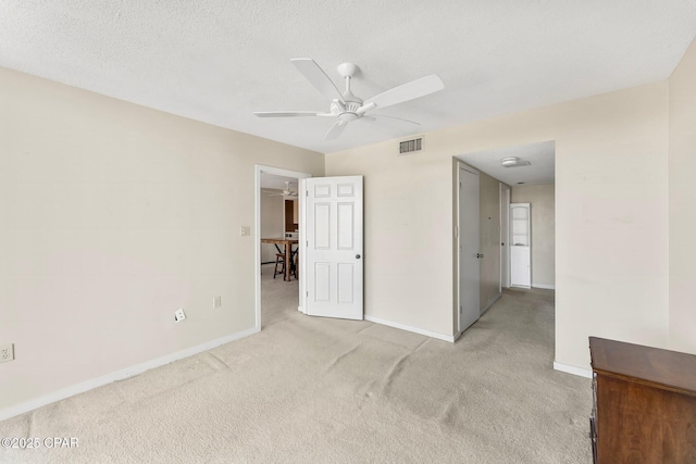 interior space featuring light carpet, a textured ceiling, visible vents, and baseboards