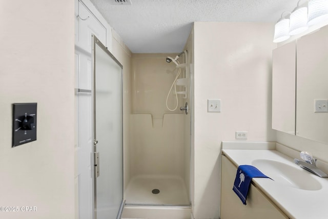 bathroom with a textured ceiling, a stall shower, and vanity