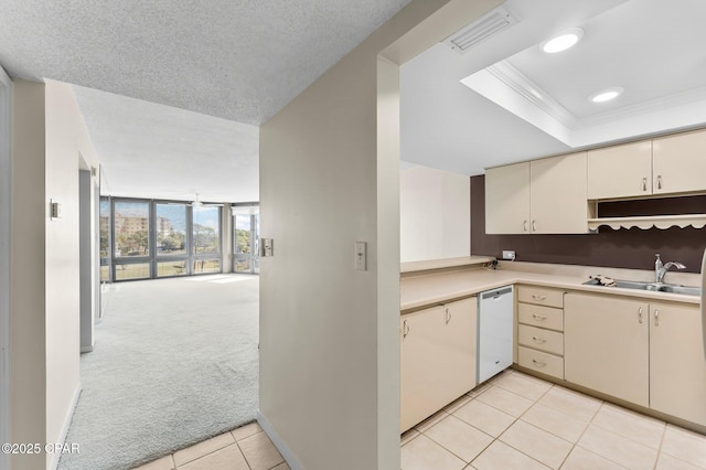 kitchen with cream cabinetry, ornamental molding, light carpet, white dishwasher, and a sink