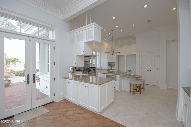 kitchen featuring white cabinetry, crown molding, light stone countertops, and kitchen peninsula