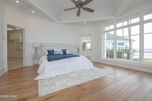 bedroom featuring multiple windows, crown molding, a spacious closet, and light hardwood / wood-style flooring