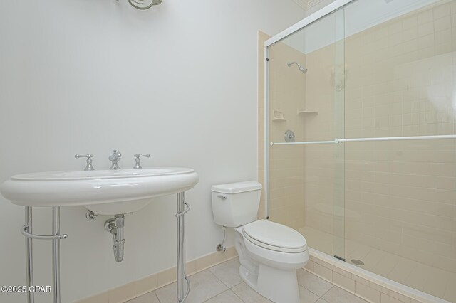 bathroom with a shower with shower door, tile patterned floors, and toilet