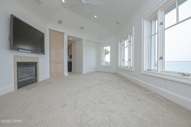 unfurnished living room featuring vaulted ceiling, a tiled fireplace, light colored carpet, ceiling fan, and crown molding