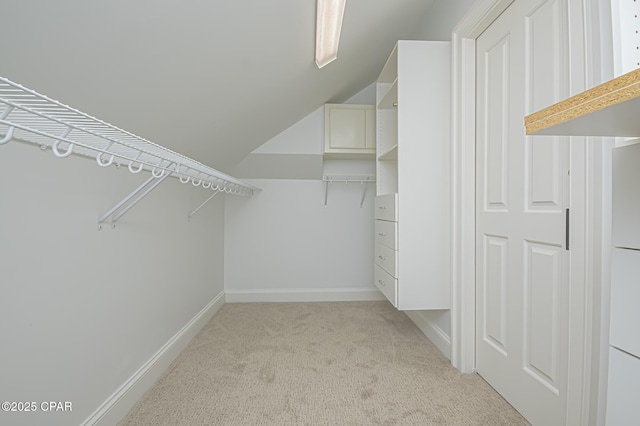 walk in closet featuring lofted ceiling and light colored carpet