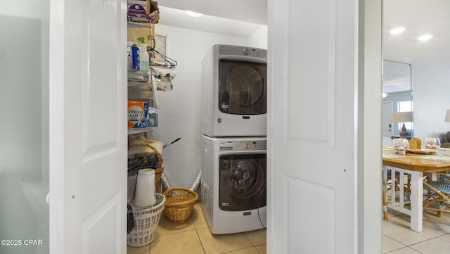 clothes washing area with stacked washer / drying machine and light tile patterned floors