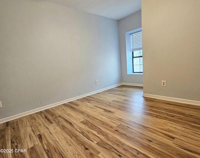 spare room featuring baseboards and wood finished floors