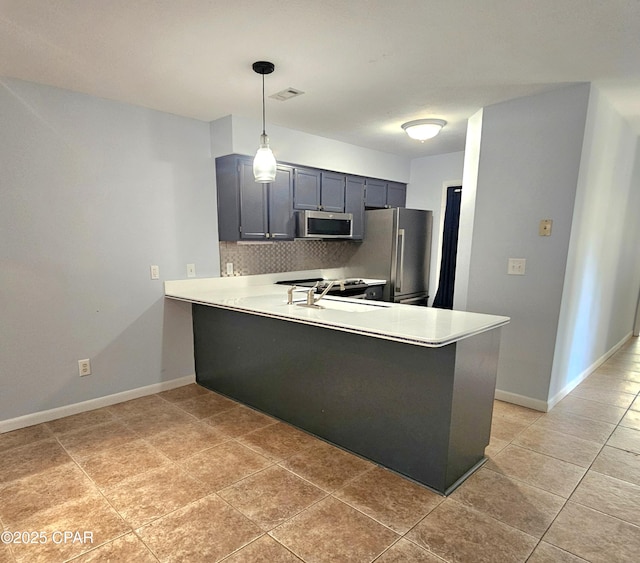 kitchen with tasteful backsplash, appliances with stainless steel finishes, a peninsula, hanging light fixtures, and light countertops