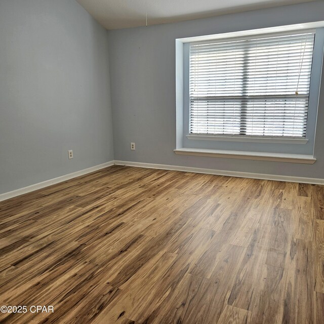 unfurnished room with baseboards and wood finished floors