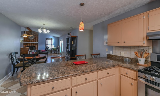 kitchen featuring stainless steel range with gas cooktop, pendant lighting, lofted ceiling, decorative backsplash, and a brick fireplace