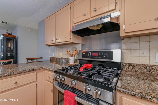 kitchen featuring dark stone countertops, decorative backsplash, gas stove, and a textured ceiling