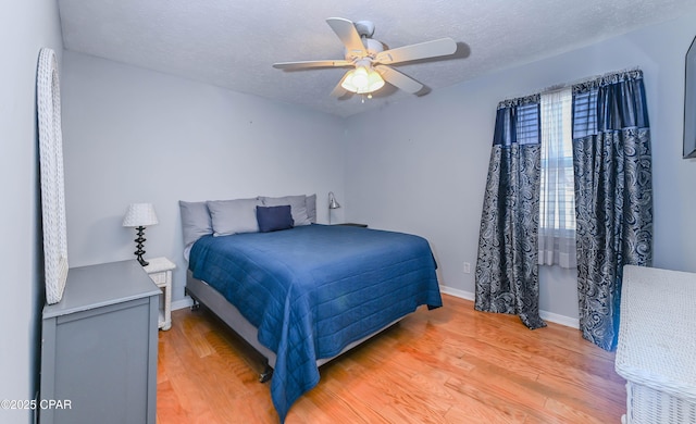 bedroom featuring ceiling fan, a textured ceiling, and light hardwood / wood-style floors