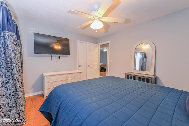 bedroom with a textured ceiling, light hardwood / wood-style floors, and ceiling fan