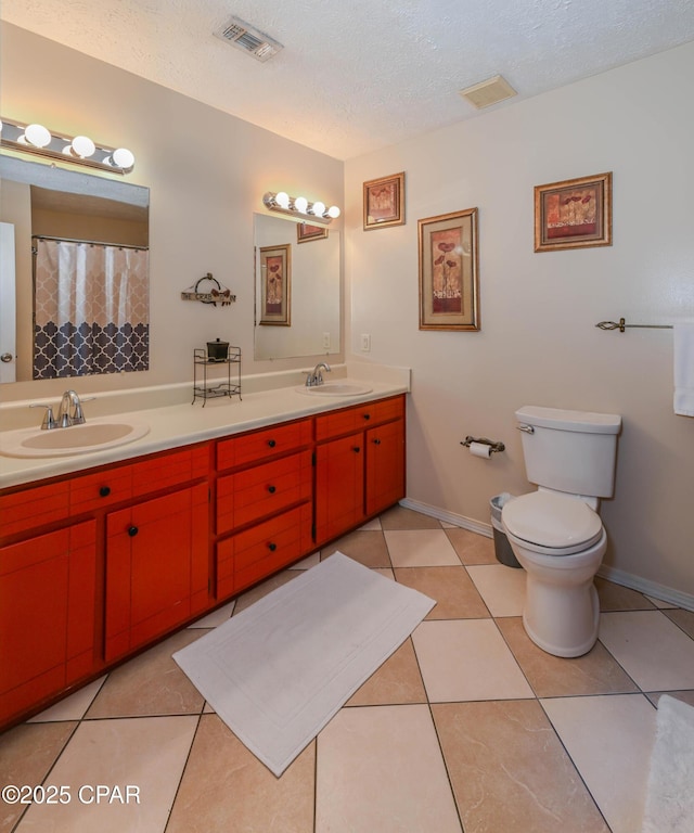 bathroom featuring vanity, tile patterned flooring, toilet, and a textured ceiling