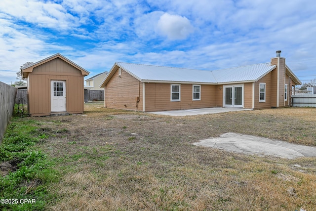 rear view of property with a shed, a yard, and a patio