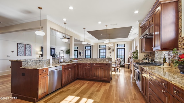 kitchen with appliances with stainless steel finishes, sink, pendant lighting, and light stone counters