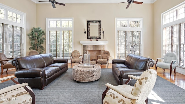 living room featuring hardwood / wood-style flooring, a brick fireplace, a healthy amount of sunlight, and ceiling fan