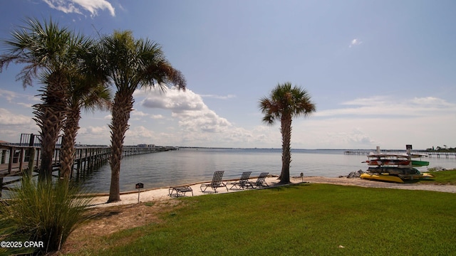 view of dock with a yard and a water view